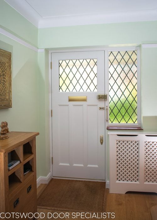 Inside of 1930s front door with leaded glass. Glazed door frame with diamond leaded glass. Brass door furniture. Inside of door painted white, viewed from hallway
