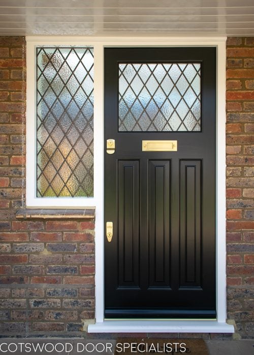 Black 1930s front door with leaded glass. Glazed door frame with diamond leaded glass. Brass door furniture