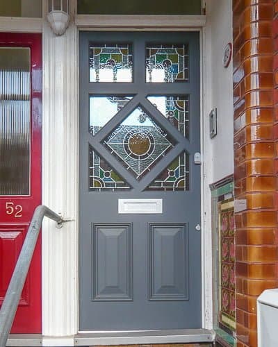 Diamond glazed Edwardian front door painted dark grey. Stained glass in door and satin chrome door furniture