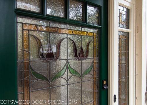 Edwardian front entrance with decorative frame. Stained glass to the door and frame. Door painted dark green. Edwardian porch. Flowers in stained glass