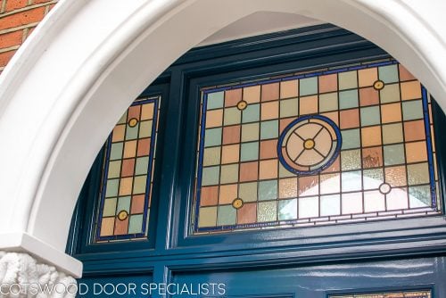 Extra wide Victorian front entrance door painted blue with stained glass. Door frame with glass to the sides and above the door