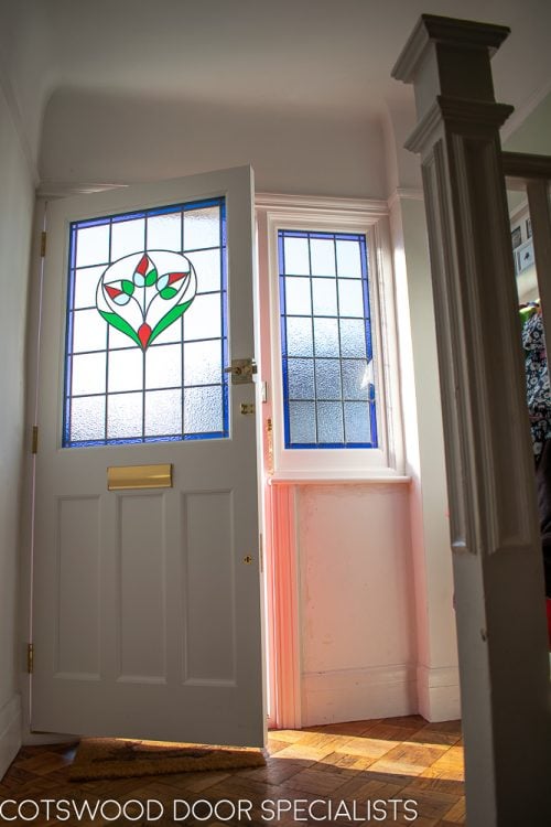 Late Edwardian red front door and sidelight frame. Shot from hallway of stained glass with light coming in