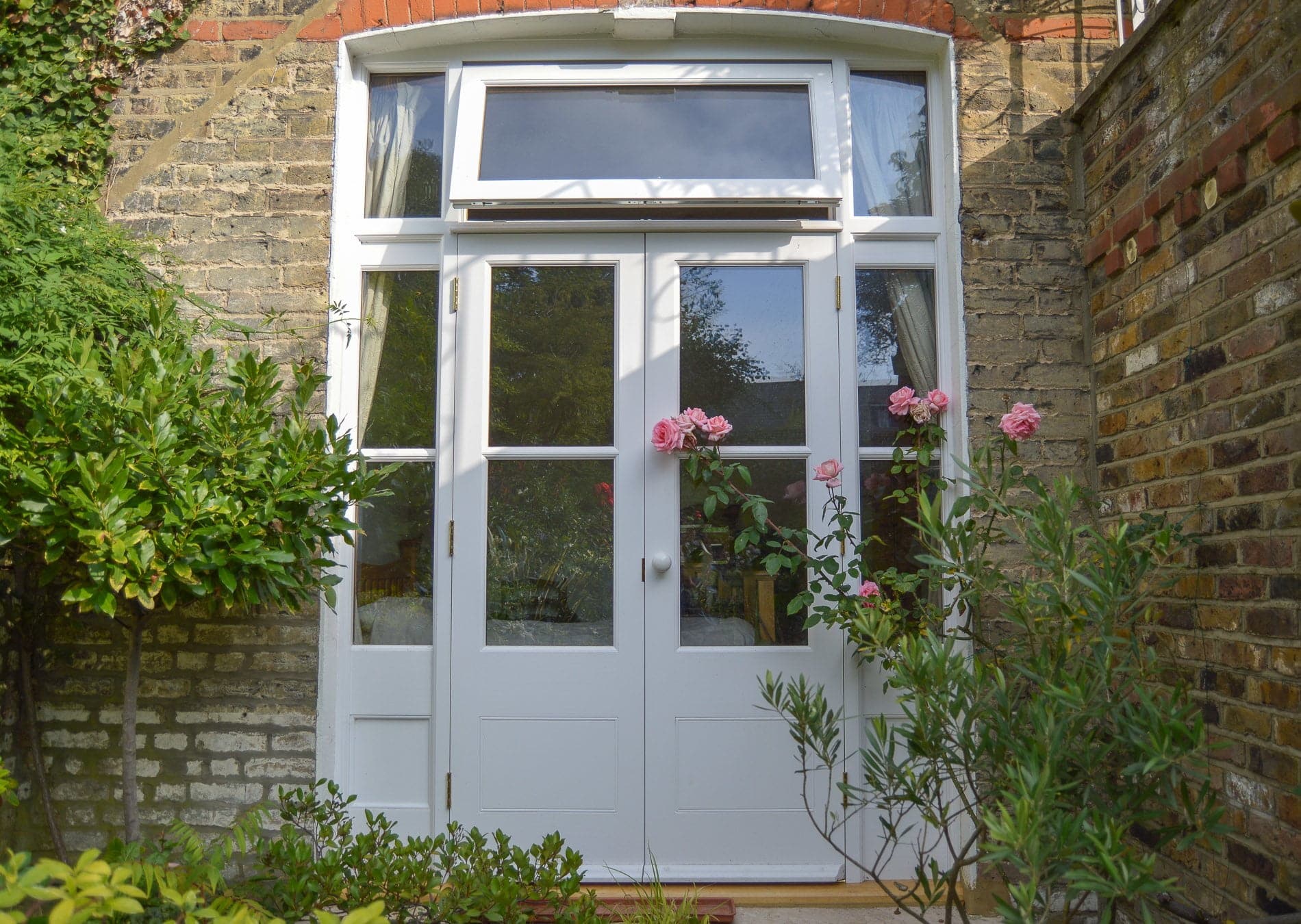 Bespoke french doors and sidelight frame. Painted white and double glazed. Opening fanlight above doors