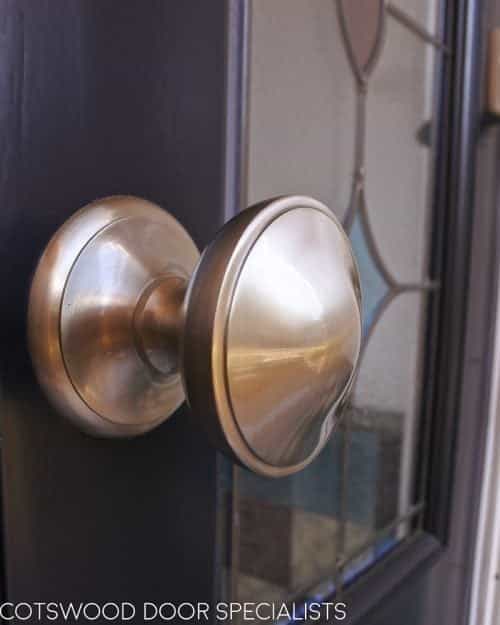 Late Victorian style dark blue painted front door. Door and frame with stained glass. Satin chrome door furniture. Closeup of door knob