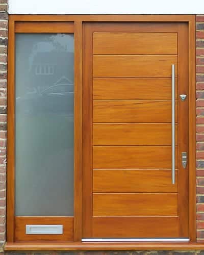 Wide boarded contemporary front door. Sidelight frame with etched glass. Simple door furniture with long bar handle. Satin chrome banham locks