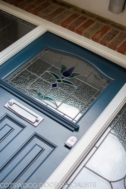 1930s stained glass front door painted farrow and ball hague blue. Double 1930s sidelight frame with brick below the sidelights. Stained glass to door and door frame. Satin chrome door furniture