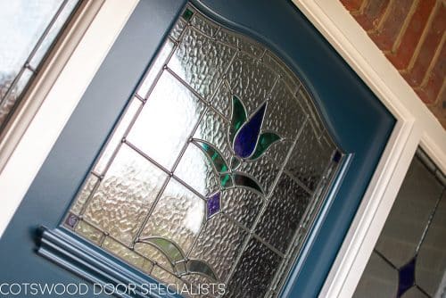 1930s stained glass front door painted farrow and ball hague blue. Double 1930s sidelight frame with brick below the sidelights. Stained glass to door and door frame. Satin chrome door furniture