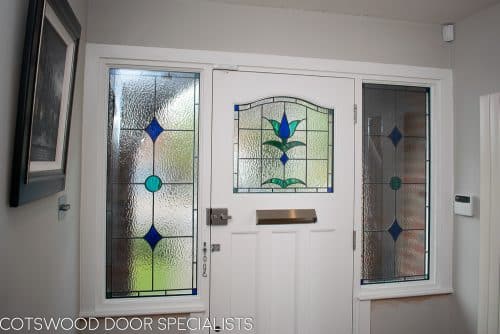 1930s stained glass front door painted farrow and ball hague blue. Double 1930s sidelight frame with brick below the sidelights. Stained glass to door and door frame. Satin chrome door furniture. View of door from inside hallway