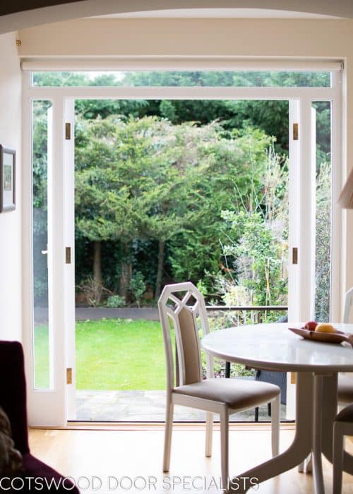 White painted wooden glazed french door with sidelight frame. Double glazed clear glass and brass hardware. Doors opening into garden