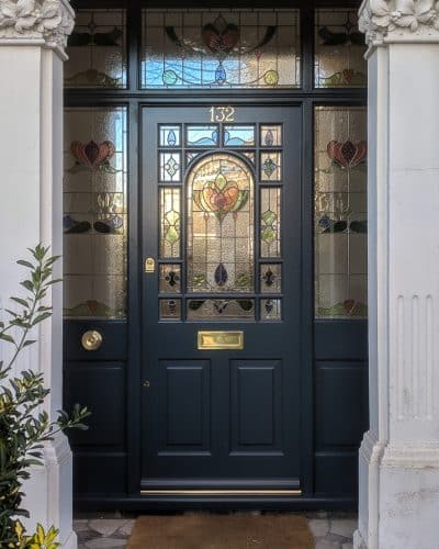 Decorative Edwardian front door with double sidelight frame. Door and frame with stained glass. Painted farrow and ball Hague blue, dark blue. Brass door furniture