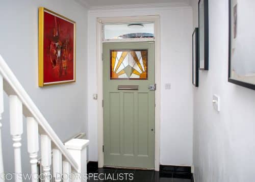 Stained glass 1930's Door. Stained glass with a geometric art deco pattern. Different colours of glass combined with different textures highlight the design. Door painted light green in colour. Satin chrome door fittings Hallway view with light shining though the stained glass