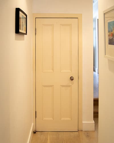 Victorian internal door. Bespoke four panelled door made with period panel moulding. Door installed in a London home. Painted finish. Antique brass door knob. View form hallway