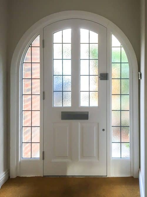 4 panel arched 1930's door, painted grey, with frame and sidelights, obscure glass with leaded oblongs, black iron furniture, fitted by our carpenters in London