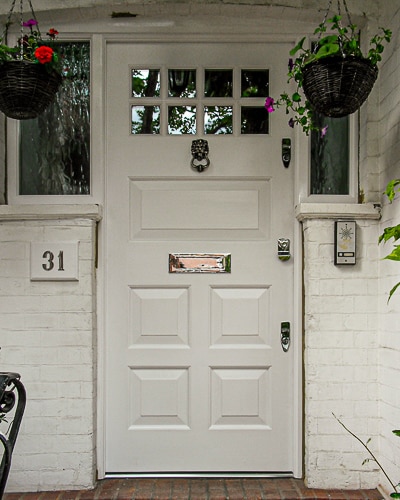 Georgian front door with glass. Clear glass in door and textured glass to door frame. Door and frame painted white. Door fitted with silver door furniture with a lion knocker.