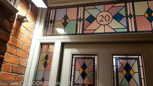 Victorian front entrance with leaded lights. Beautiful geometric stained glass design with number above door. All fully painted light grey. Door furniture is smooth black finish. Closeup of transom fanlight