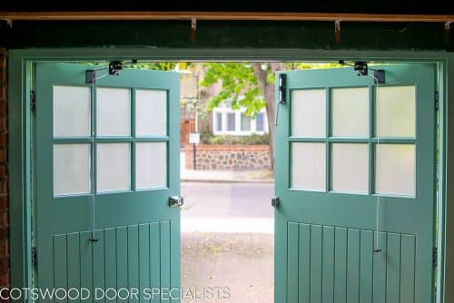 1930s art deco garage doors. Classic 1930's side hinged garage doors with glazing. Glazing is divided into 6 pieces per door with wooden glazing bar. Obscured glass. Painted light green. Tongue and groove style boarding. polished chrome door furniture.