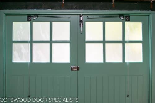 1930s art deco garage doors. Classic 1930's side hinged garage doors with glazing. Glazing is divided into 6 pieces per door with wooden glazing bar. Obscured glass. Painted light green. Tongue and groove style boarding. Polished chrome door furniture. Door stays fitted.