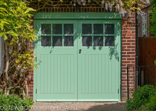 1930s art deco garage doors. Classic 1930's side hinged garage doors with glazing. Glazing is divided into 6 pieces per door with wooden glazing bar. Obscured glass. Painted light green. Tongue and groove style boarding. Polished chrome door furniture.