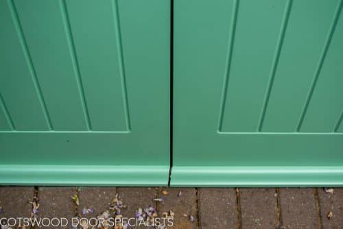 1930s art deco garage doors. Classic 1930's side hinged garage doors with glazing. Glazing is divided into 6 pieces per door with wooden glazing bar. Obscured glass. Painted light green. Tongue and groove style boarding. Polished chrome door furniture. Close up of lower door.