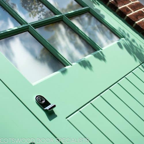 1930s art deco garage doors. Classic 1930's side hinged garage doors with glazing. Glazing is divided into 6 pieces per door with wooden glazing bar. Obscured glass. Painted light green. Tongue and groove style boarding. polished chrome door furniture. CLose up of obscure glazing.