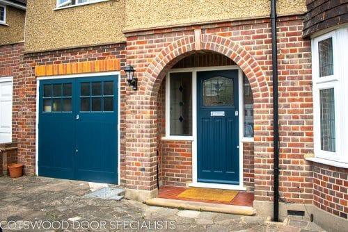 1930s wooden garage doors with matching front door. Fitted into a 1930s house with red brickwork. Doors painted dark blue. Front door has stained glass, garage doors have traditional textured obscure glass. Satin chrome door hardware