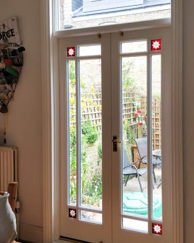 Victorian fully glazed french door with glory star . French door pair set into Victorian yellow stock brickwork. Wooden doors are painted white. Glass is double glazed with glory star red corners. Internal shot showing off brilliant cut red glory stars