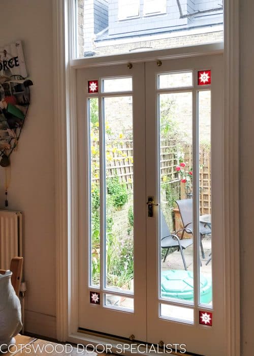 Victorian fully glazed french door with glory star . French door pair set into Victorian yellow stock brickwork. Wooden doors are painted white. Glass is double glazed with glory star red corners. Internal shot showing off brilliant cut red glory stars