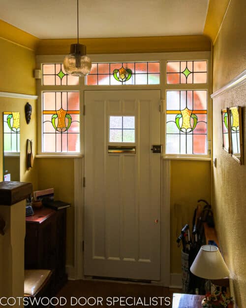 1920s Front door fitted into an arch, making an open storm porch. door is painted light green with a red brick arch surrounding. Door and door frame have stained leaded glass. Door has recessed flat panels for a non fussy appearance. Inside shot of 1930s hallway with stained glass in the front door