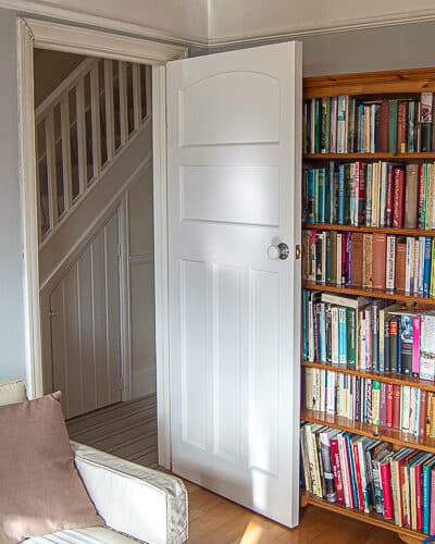 1930s Bespoke Internal door. Door fitted entering a living room. 1930s door has recessed flat panels and is solid with no glazing. Door is fully painted white and installed with a white porcelain door knob.