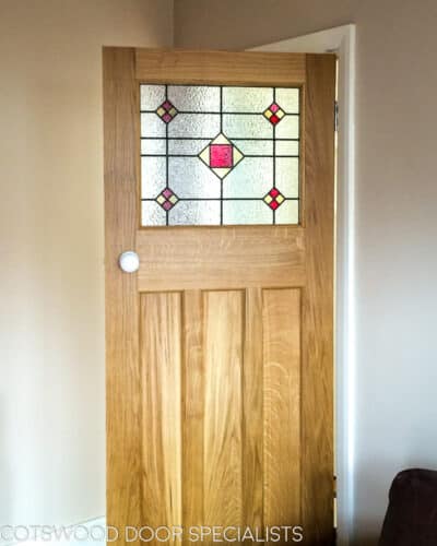 1930s stained glass internal door. Classic solid oak internal door fitted with stained glass panel in top third of door. White porcelain door knobs. Prime Quarter sawn oak panels with medullary rays