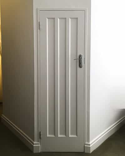 Art Deco 1930s internal door. Fully painted white and fitted with chrome door handle. Fitted into a london home. Row of three long vertical panels of art deco design to door