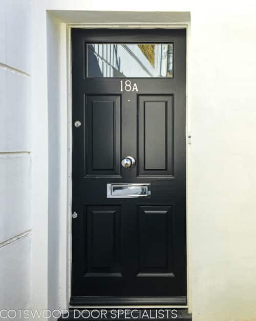 Black Georgian front door. Door fitted into London home basement appartment. Black door with clear glass double glazed top panel. Door furniture is polished chrome.