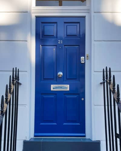 Blue Georgian front door. Painted in gloss blue paint fitted with polished chrome door furniture. Classic london doorway with door fitted at top of steps on the outside of the home.