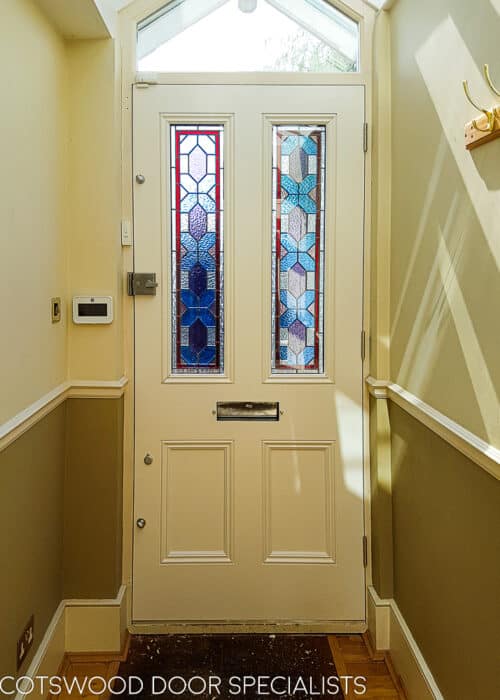 Blue Victorian door door has geometric stained glass . 2 Panels of stained glass in a classic Victorian front door. Different textures and colours in the stained glass. Door frame has an double raked head and is fitted with sandblasted glass with a number. Satin chrome door furniture. Internal hallway shot showing off the victorian stained glass