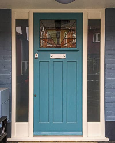 Teal 1920s door. Door has is fitted into a double sidelight frame, painted white with etched glass. The door has a geometric stained glass.