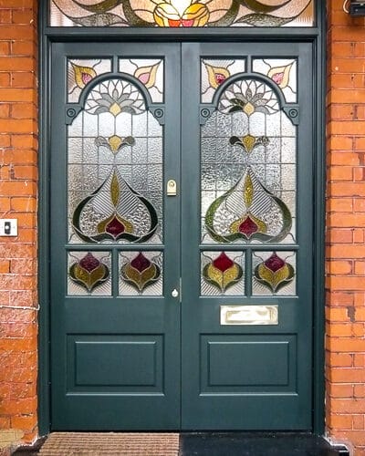 Decorative Edwardian double doors fitted into a large red bricked Edwardian London home. Beautiful stained glass design to doors with decorative fanlight. doors painted a rich green colour