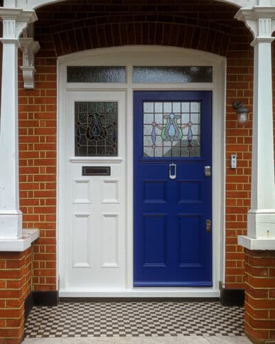 Edwardian entrance door. Door has multiple panels and the frame has a matching design. Door and frame are fitted into a red brick arch. Door and frame have stained glass.
