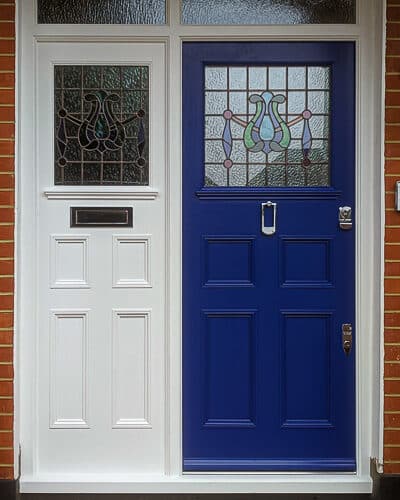Edwardian entrance door. Door has multiple panels and the frame has a matching design. Door and frame are fitted into a red brick arch. Door and frame have stained glass.