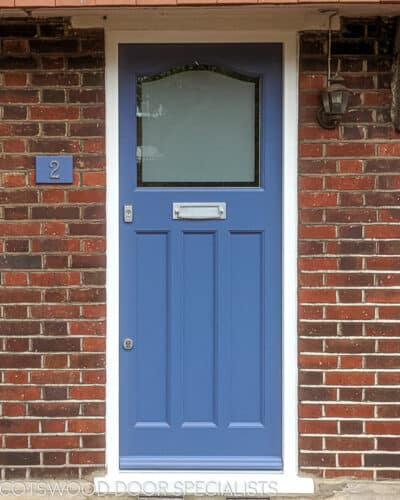 Etched glass 1930s door. Wooden door is painted blue fitted into a red brick london home. Door has etched glass with a simple clear border. Door furniture is stain chrome. New door frame is painted white