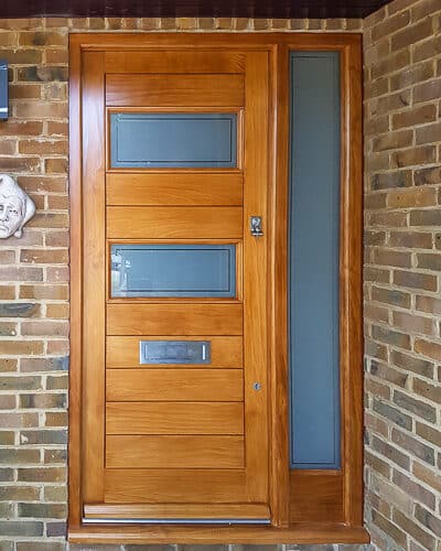 Modern stained wooden door. Beautiful grain to Accoya wooden front door. Door has glazing and a side panel of glass