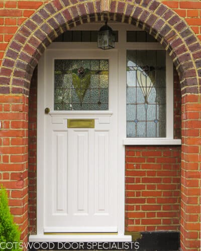 Multipoint locking 1930s door. White painted front door and frame with stained glass. Door has antique brass door furniture and a modern multipoint locking system