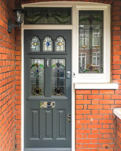 Stained glass Edwardian door. Art nouveaux style stained glass fitted into a decorative grey Edwardian door. Door frame also has stained glass. London home with red brickwork