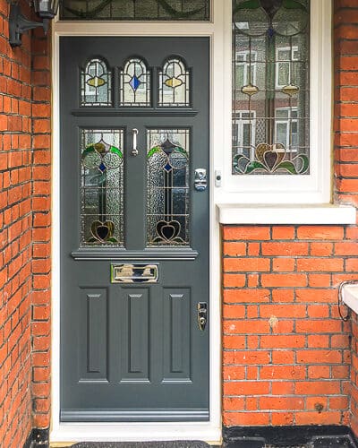 Stained glass Edwardian door. Art nouveaux style stained glass fitted into a decorative grey Edwardian door. Door frame also has stained glass. London home with red brickwork