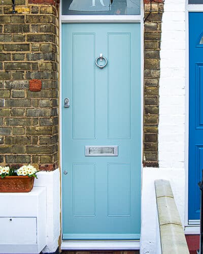 Traditional Victorian Front door fitted into a London terraced house. House is built with yellow stock bricks. Door frame has a fanlight that is fitted behind an arch. Door is painted a light blue colour and has tradtional butt and beaded panels. etched glass to transom with number