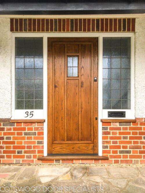 Tudor style door. 1930s style tudor door in natural wood. door has small piece of leaded glass and applied wooden ribbing. Sidelight frame is painted white and has leaded glass.