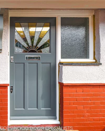 1930s Sunburst door. 1930s front door fitted into a brick and render london home. 1930s art deco stained glass in yellow, red and green. Door is painted grey and frame is painted white.