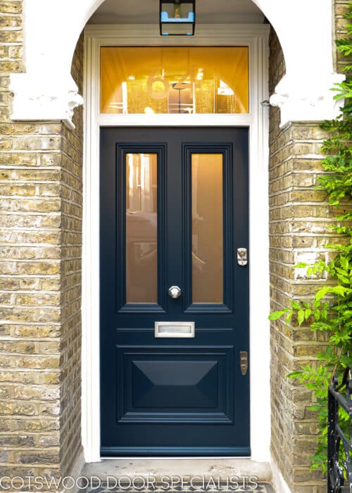 Beaded Victorian door. Victorian front door painted dark blue. fitted into a yellow stock brick london home. Door has 2 panels of glass and 1 raised cricket bat panel. The midrail around letterplate has a special horizontal bead detail replicating the original local joinery. Etched glass to door and number to frame