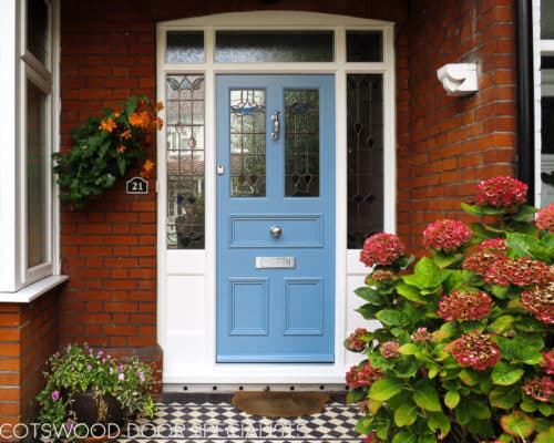 Blue Edwardian Entrance door. Large Edwardian front entrance with central door and double sidelight and fanlight frame. Door and frame have complimentary stained glass. Wooden door is painted blue and frame white. Fitted into a London red brick home