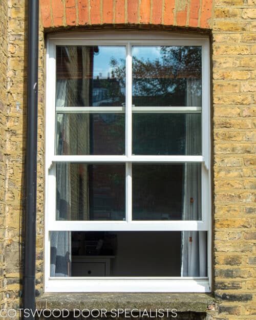 Classic box sash window. 2 over 2 window with vertical glazing bar. Sliding box sash fitted into yellow stock brick London terraced house. Double glazed window and white painted wooden window