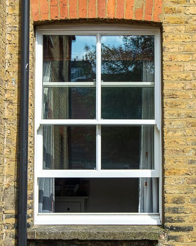 Classic box sash window. 2 over 2 window with vertical glazing bar. Sliding box sash fitted into yellow stock brick London terraced house. Double glazed window and white painted wooden window